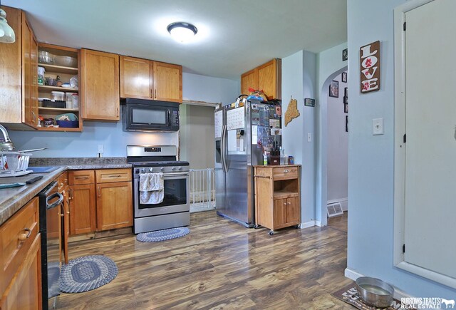 429 N 4th St, Tecumseh, NE 68450 - kitchen with appliances with stainless steel finishes, dark wood-style flooring, open shelves, brown cabinets, and arched walkways