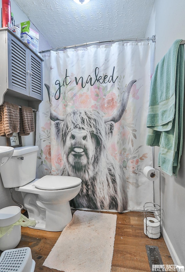 429 N 4th St, Tecumseh, NE 68450 - full bath featuring toilet, wood finished floors, a textured ceiling, a shower with shower curtain, and baseboards