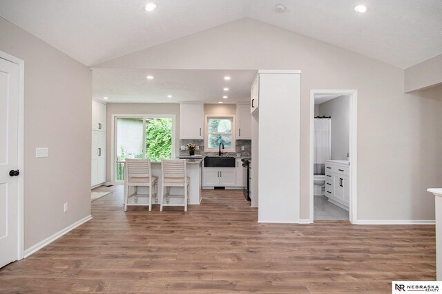 606 Pioneer Dr, Fort Calhoun, NE 68023 - kitchen featuring white cabinetry, vaulted ceiling, light wood-type flooring, a kitchen bar, and recessed lighting