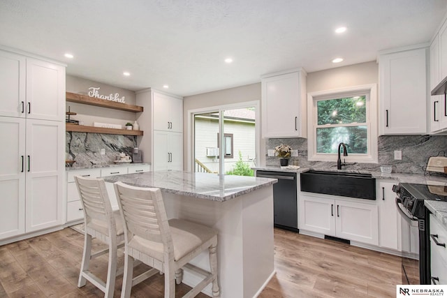 606 Pioneer Dr, Fort Calhoun, NE 68023 - kitchen with dishwashing machine, black range oven, a sink, open shelves, and light wood-type flooring