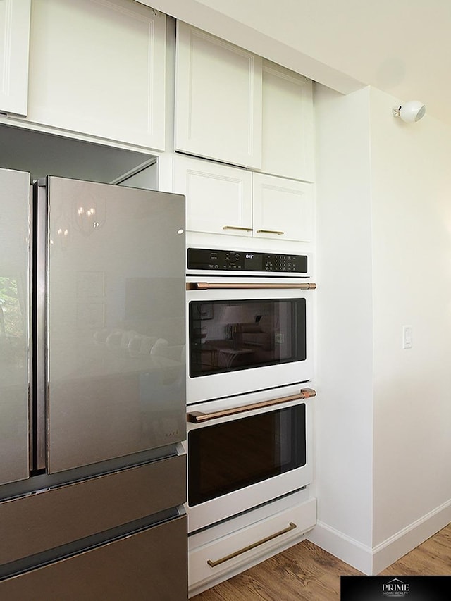 20640 Rawhide Rd, Omaha, NE 68022 - kitchen with freestanding refrigerator, white double oven, wood finished floors, baseboards, and white cabinets