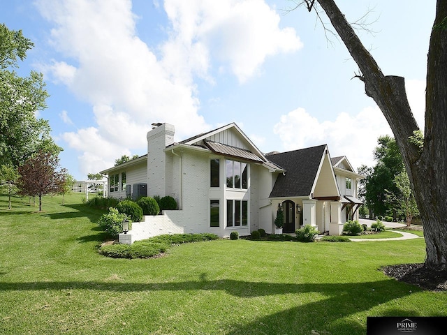 20640 Rawhide Rd, Omaha, NE 68022 - back of house featuring a chimney, a lawn, brick siding, and central AC
