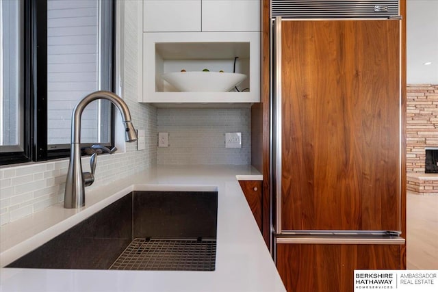 1312 S 78th St, Omaha, NE 68124 - kitchen view of paneled fridge, a sink, tasteful backsplash, and white cabinetry