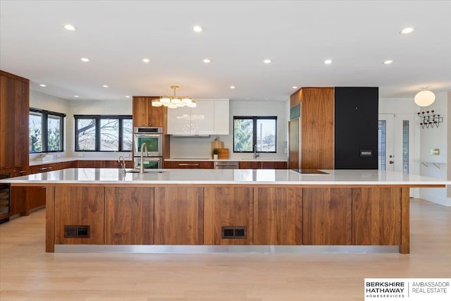 1312 S 78th St, Omaha, NE 68124 - kitchen featuring stainless steel appliances, light wood-style flooring, white cabinetry, a chandelier, and recessed lighting