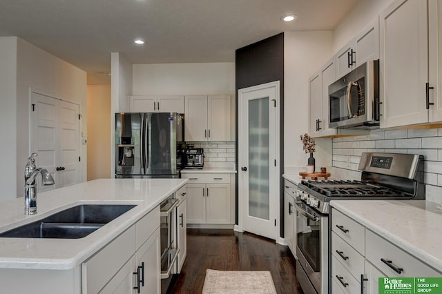 10505 Rosewater Pkwy, Bennington, NE 68007 - kitchen featuring appliances with stainless steel finishes, a sink, dark wood-style flooring, decorative backsplash, and recessed lighting