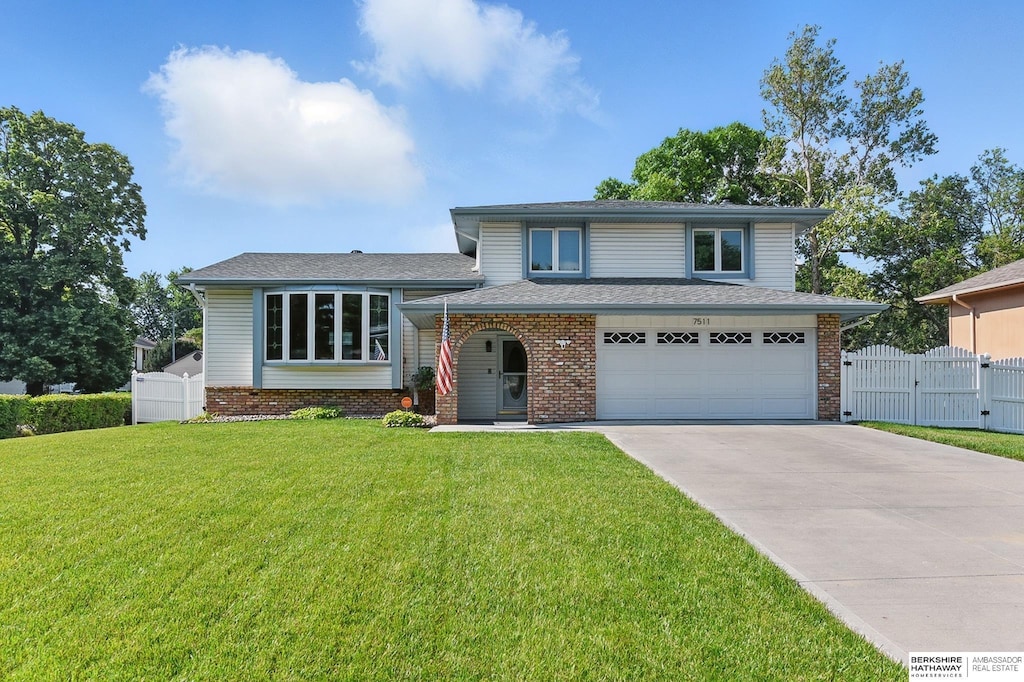 7511 Drexel St, Ralston, NE 68127 - split level home with concrete driveway, an attached garage, a gate, and brick siding