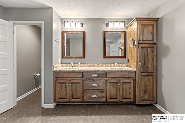 1220 S 200th Ave, Omaha, NE 68130 - bathroom featuring double vanity, baseboards, wood finish floors, and a textured ceiling