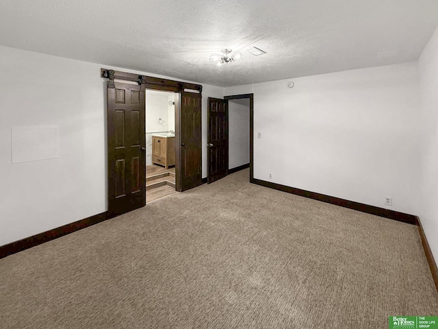 8259 Paradise Hills Ln, Fort Calhoun, NE 68023 - unfurnished bedroom featuring baseboards, light colored carpet, a textured ceiling, a barn door, and ensuite bath