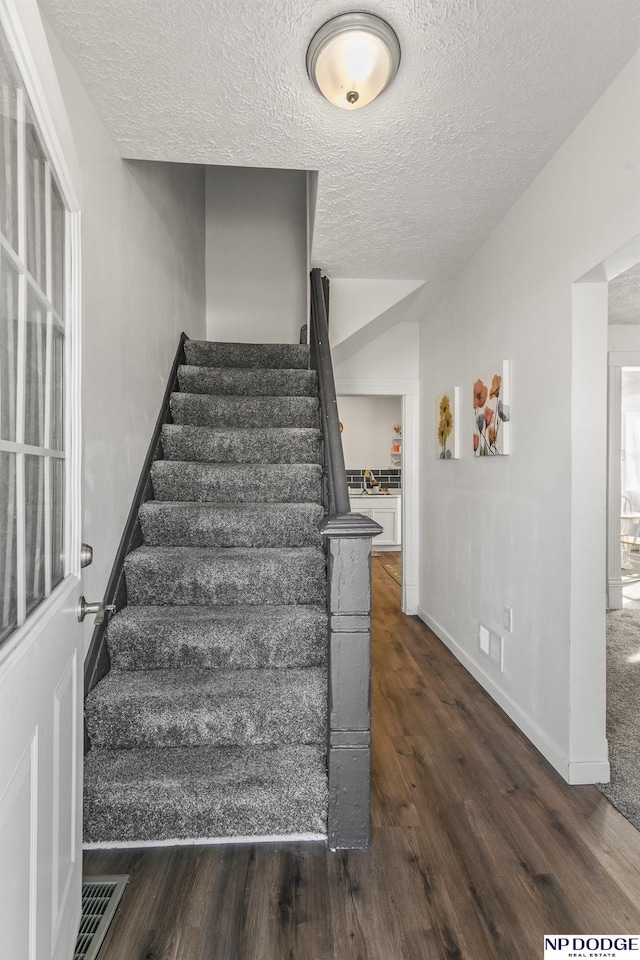 5335 N 26th St, Omaha, NE 68111 - staircase featuring wood finished floors, a textured ceiling, and baseboards