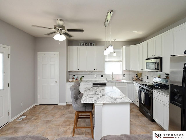7941 N 152nd St, Bennington, NE 68007 - kitchen featuring appliances with stainless steel finishes, a sink, decorative backsplash, ceiling fan, and a center island