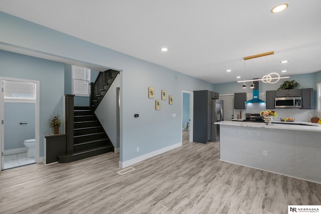 2306 Ogden St, Omaha, NE 68110 - kitchen with stainless steel appliances, wall chimney exhaust hood, light countertops, light wood finished floors, and recessed lighting