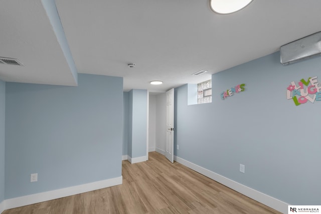 2306 Ogden St, Omaha, NE 68110 - basement with light wood finished floors, baseboards, and a wall mounted air conditioner