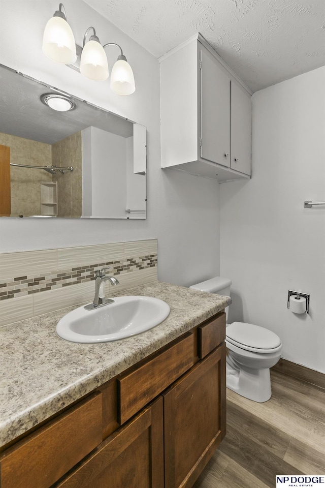 9607 Spencer St, Omaha, NE 68134 - bathroom featuring backsplash, vanity, wood finished floors, toilet, and a shower