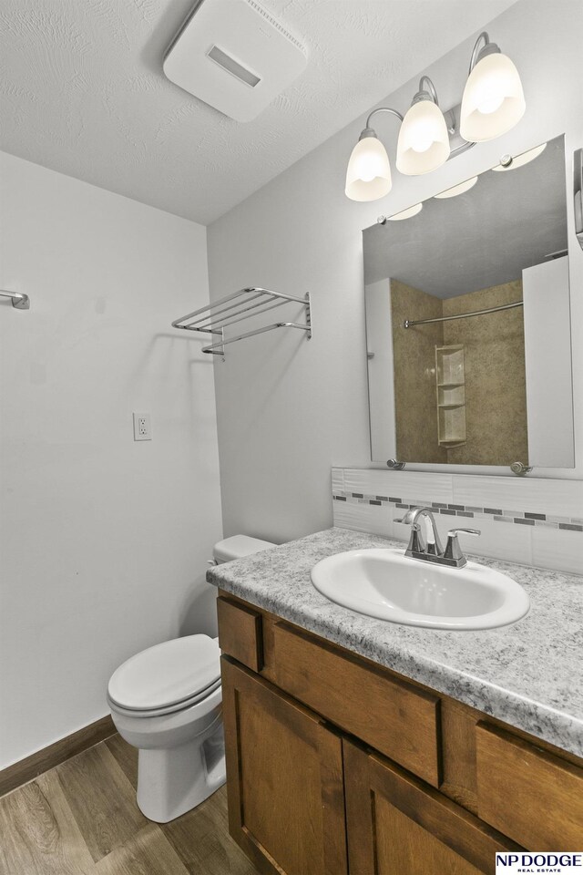9607 Spencer St, Omaha, NE 68134 - full bath with wood finished floors, decorative backsplash, vanity, toilet, and a shower