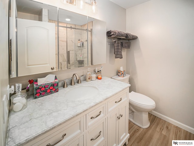 139 N 11th St Unit 905, Lincoln, NE 68508 - bathroom featuring vanity, toilet, wood finished floors, a stall shower, and baseboards