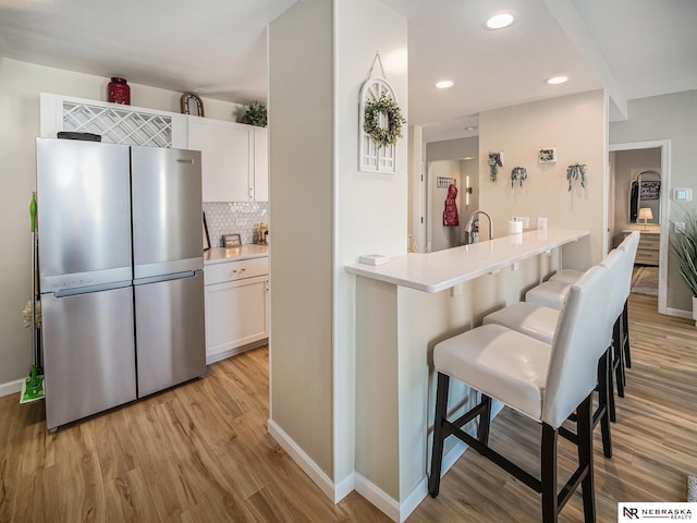 139 N 11th St Unit 905, Lincoln, NE 68508 - kitchen with freestanding refrigerator, a breakfast bar, light wood finished floors, white cabinetry, and recessed lighting