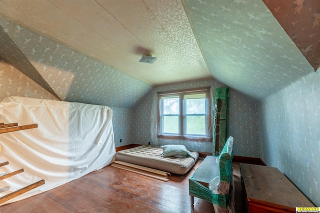 102 Eldon St, Talmage, NE 68448 - bedroom featuring hardwood / wood-style floors, wallpapered walls, vaulted ceiling, and a textured ceiling