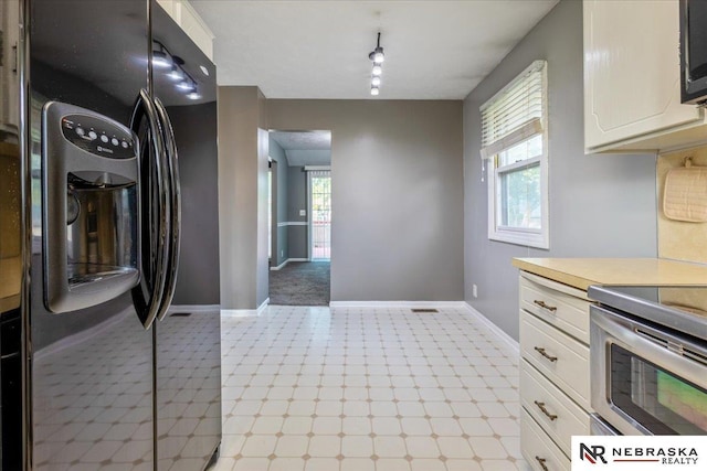 15161 R St, Omaha, NE 68137 - kitchen with black refrigerator with ice dispenser, light flooring, white cabinetry, and baseboards