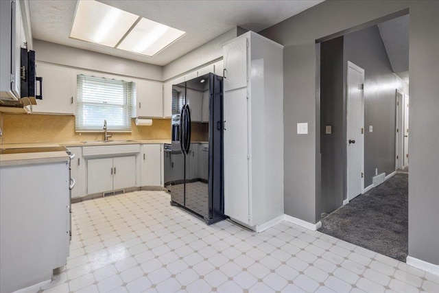 15161 R St, Omaha, NE 68137 - kitchen with black refrigerator with ice dispenser, a sink, light countertops, light flooring, and white cabinetry