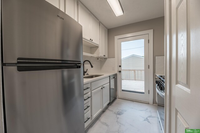5515 Hickory St, Omaha, NE 68106 - kitchen featuring stainless steel appliances, a sink, light marble finish floors, white cabinetry, and tasteful backsplash