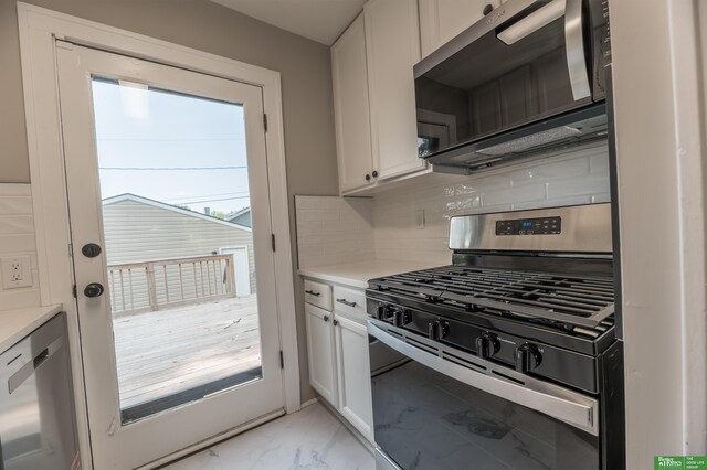 5515 Hickory St, Omaha, NE 68106 - kitchen with stainless steel appliances, light marble finish flooring, white cabinetry, and tasteful backsplash