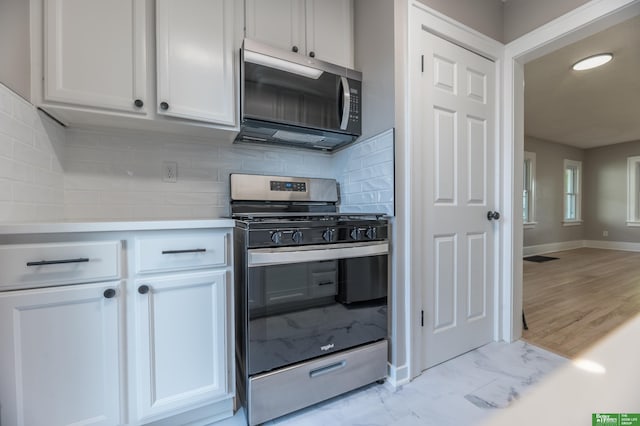 5515 Hickory St, Omaha, NE 68106 - kitchen with stainless steel appliances, baseboards, decorative backsplash, light countertops, and white cabinetry