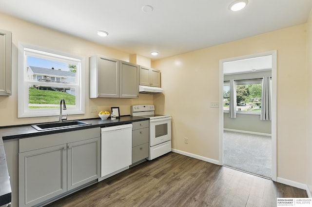3847 Valley St, Omaha, NE 68105 - kitchen with white appliances, under cabinet range hood, dark countertops, dark wood-style floors, and recessed lighting