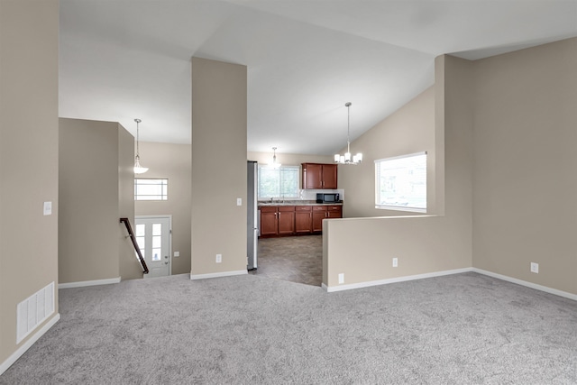 16421 Redman Ave, Omaha, NE 68116 - unfurnished living room featuring healthy amount of natural light, a chandelier, carpet flooring, and high vaulted ceiling
