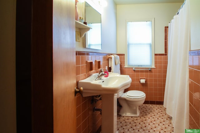 3855 Dewey Ave, Omaha, NE 68105 - full bath with tile walls, toilet, a wainscoted wall, tile patterned floors, and a shower with curtain