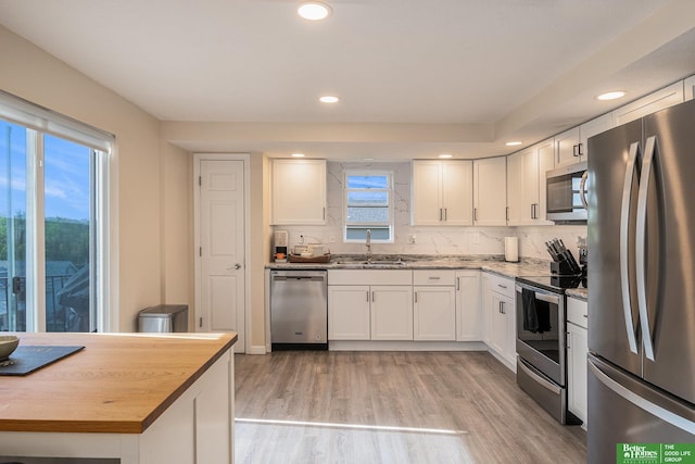 601 5th Ave, Plattsmouth, NE 68048 - kitchen with stainless steel appliances, a sink, white cabinets, light wood-style flooring, and wooden counters