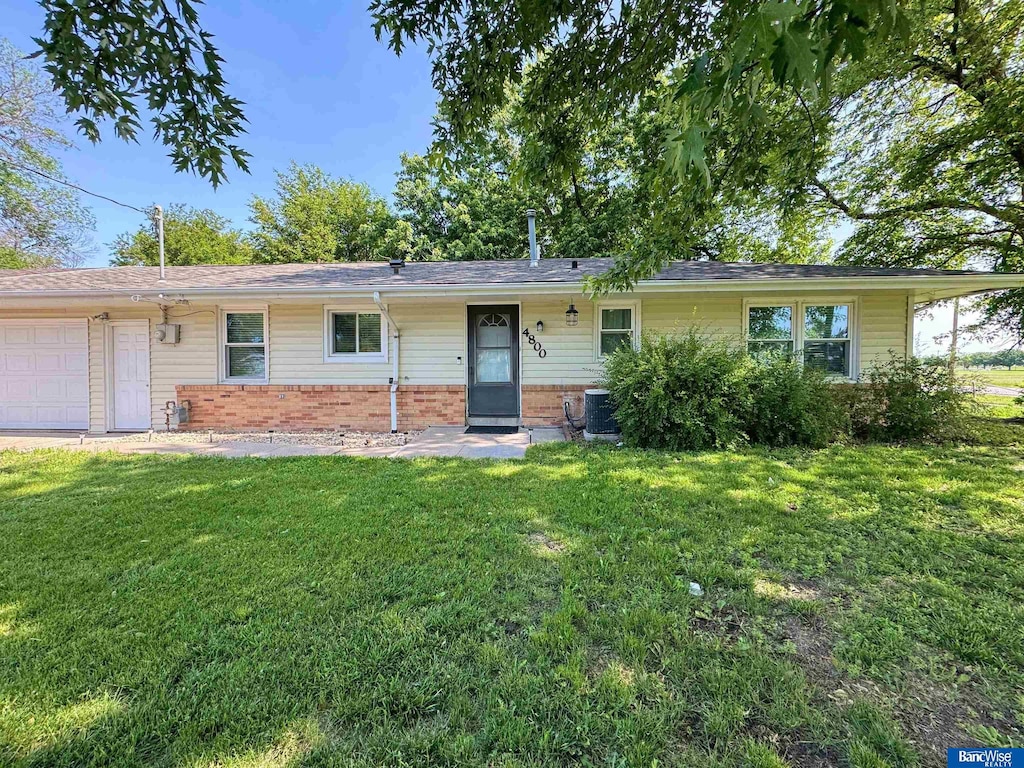4800 W Vosler St, Lincoln, NE 68524 - ranch-style home with a garage, a front yard, brick siding, and central air condition unit