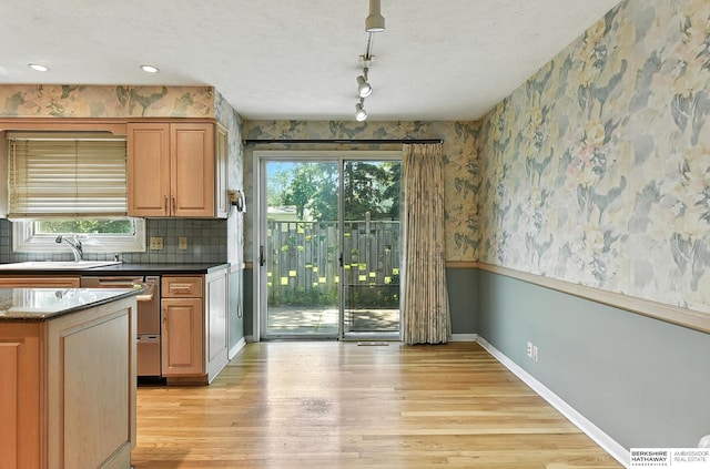 3629 S 114th Ave, Omaha, NE 68144 - kitchen featuring light wood-type flooring, wallpapered walls, healthy amount of natural light, stainless steel dishwasher, and a textured ceiling