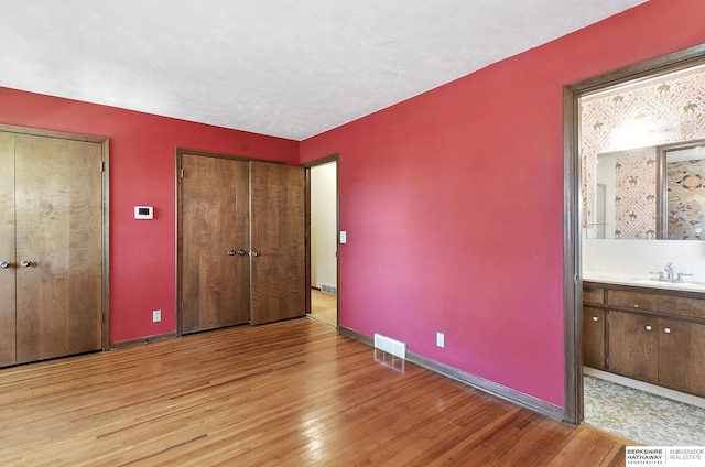 3629 S 114th Ave, Omaha, NE 68144 - unfurnished bedroom with light wood finished floors, multiple closets, and ensuite bath