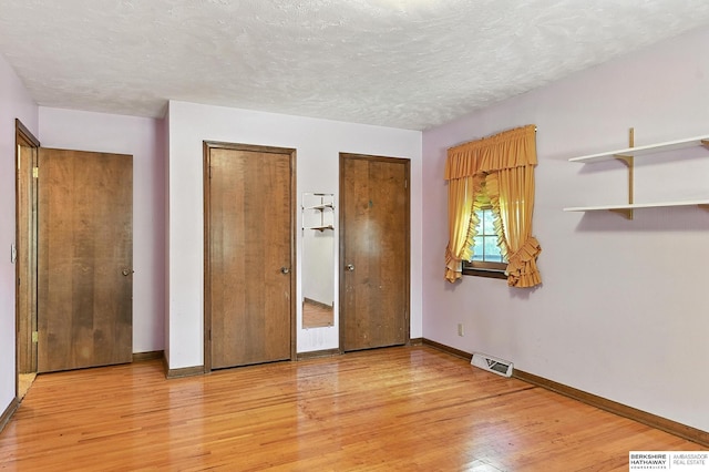 3629 S 114th Ave, Omaha, NE 68144 - unfurnished bedroom with multiple closets, light wood-type flooring, and a textured ceiling