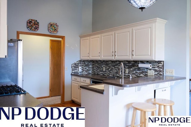 611 Diamond Ln, Papillion, NE 68133 - kitchen with tasteful backsplash, a breakfast bar, a peninsula, stovetop, and a towering ceiling