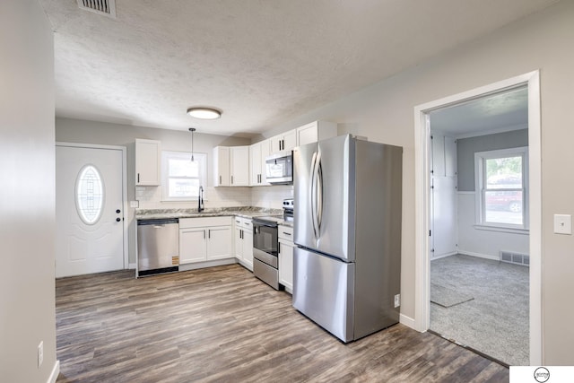 1801 Elk St, Beatrice, NE 68310 - kitchen featuring stainless steel appliances, a sink, dark wood-type flooring, white cabinetry, and decorative backsplash