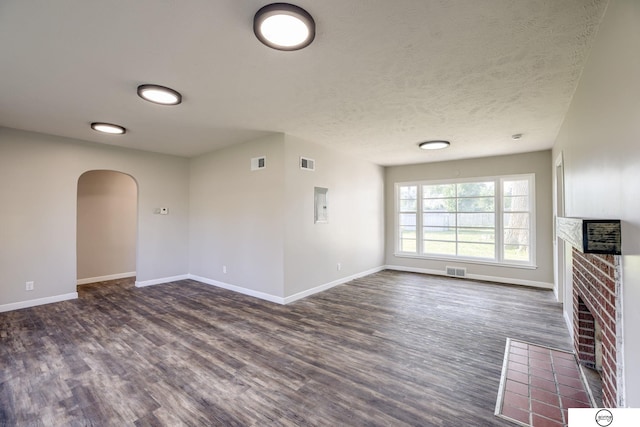 1801 Elk St, Beatrice, NE 68310 - unfurnished living room featuring a fireplace, dark wood-style flooring, arched walkways, baseboards, and a textured ceiling
