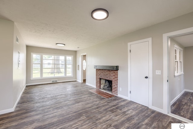 1801 Elk St, Beatrice, NE 68310 - unfurnished living room with dark wood-type flooring, baseboards, a brick fireplace, and a textured ceiling