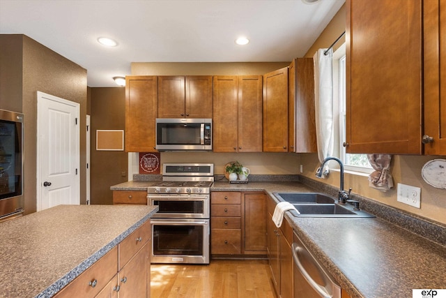 8815 N Hws Cleveland Blvd, Bennington, NE 68007 - kitchen with stainless steel appliances, a sink, light wood-style flooring, brown cabinets, and dark countertops