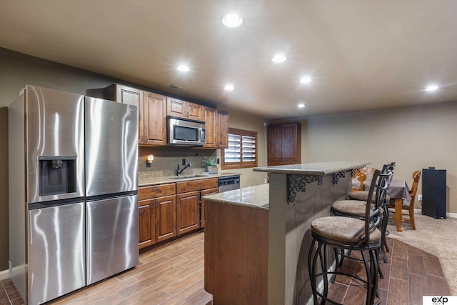 8815 N Hws Cleveland Blvd, Bennington, NE 68007 - kitchen with stainless steel appliances, a sink, a breakfast bar, recessed lighting, and light stone countertops