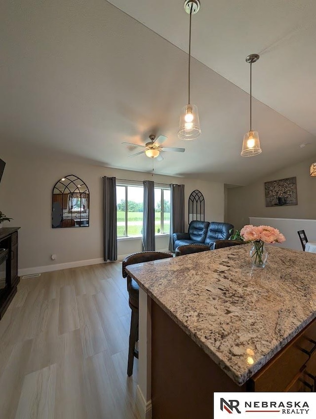 2496 Rock Creek Rd, Bee, NE 68314 - kitchen featuring light wood-style floors, ceiling fan, light stone counters, hanging light fixtures, and baseboards