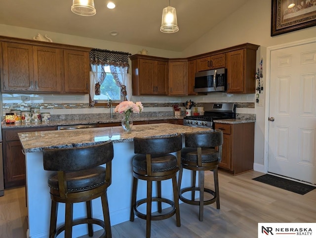 2496 Rock Creek Rd, Bee, NE 68314 - kitchen featuring appliances with stainless steel finishes, a center island, lofted ceiling, a breakfast bar, and light stone counters