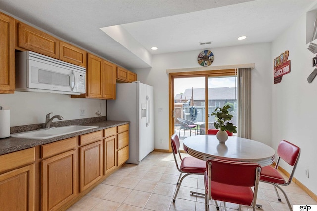 17205 Jessica Ln, Gretna, NE 68028 - kitchen featuring white appliances, dark countertops, light tile patterned floors, brown cabinets, and recessed lighting