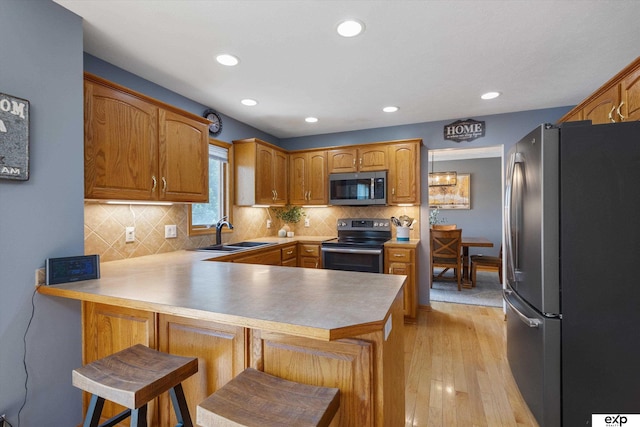 17205 Jessica Ln, Gretna, NE 68028 - kitchen with appliances with stainless steel finishes, a peninsula, light wood-style flooring, tasteful backsplash, and recessed lighting
