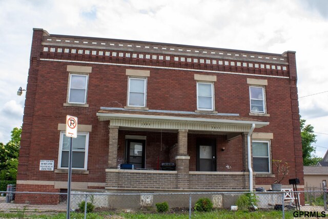 2609 Marcy St, Omaha, NE 68105 - view of front facade featuring a porch, brick siding, and a fenced front yard