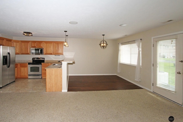 6028 Glenbrook Ln, Lincoln, NE 68512 - kitchen with stainless steel appliances, light countertops, a sink, a peninsula, and decorative light fixtures