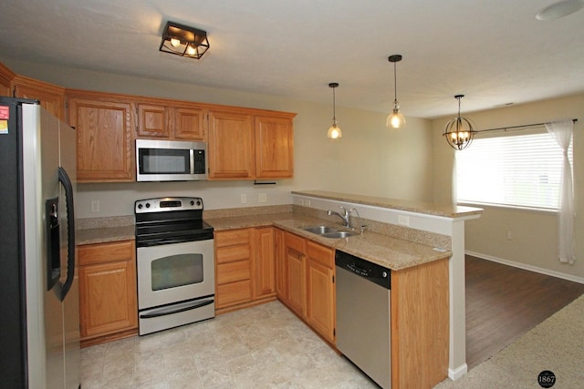 6028 Glenbrook Ln, Lincoln, NE 68512 - kitchen featuring stainless steel appliances, a sink, a peninsula, hanging light fixtures, and light stone counters