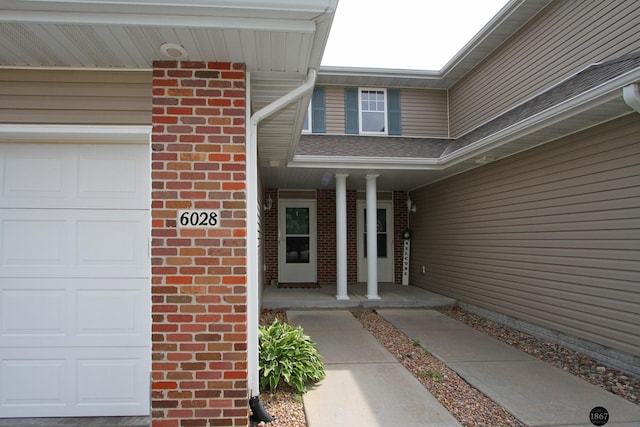 6028 Glenbrook Ln, Lincoln, NE 68512 - doorway to property with a garage, brick siding, and a porch