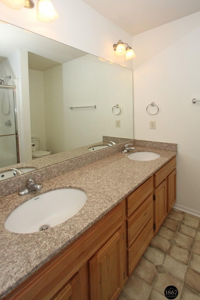 6028 Glenbrook Ln, Lincoln, NE 68512 - bathroom featuring toilet, double vanity, and a stall shower