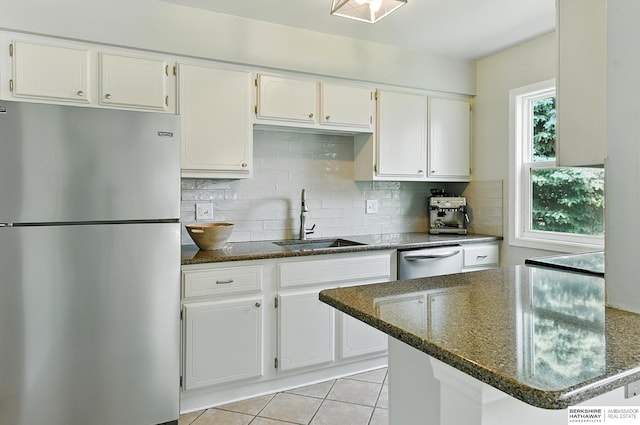 9704 Erskine St, Omaha, NE 68134 - kitchen featuring appliances with stainless steel finishes, white cabinetry, backsplash, dark stone countertops, and light tile patterned floors